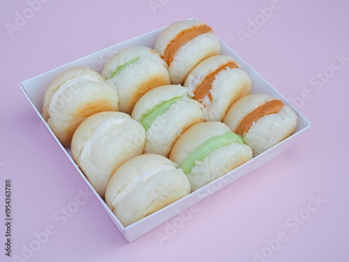 Photos Mini buns filled with cream, pandan custard, and Thai tea custard are arranged in a box