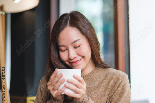Portrait image of a woman with closed eyes holding and drinking hot coffee