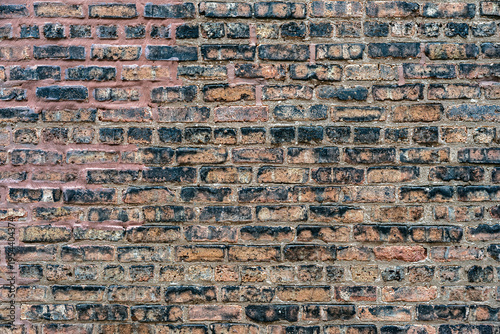 Fragment of a part of the wall of a house made of old red brick for use as an abstract background and text.
