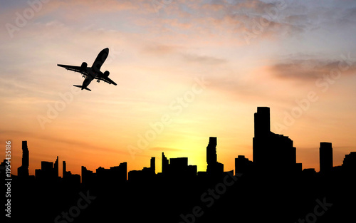 An airplane flies over a city skyline at sunset. The silhouette of an aircraft is seen soaring through the colorful sky