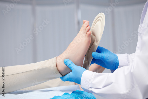 Bild auf Leinwand Doctor Fitting Orthopedic Insoles to Patient Foot
