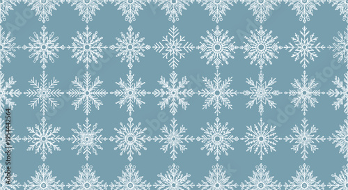 Seamless winter pattern with white hand drawn snowflakes of various shapes and sizes on a soft muted blue background.
