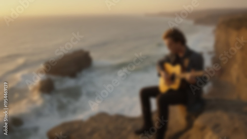 Blurred background of guitarist performing on a cliff edge overlooking crashing ocean waves, wind blowing clothes dramatically, sunset time, golden dramatic lighting.