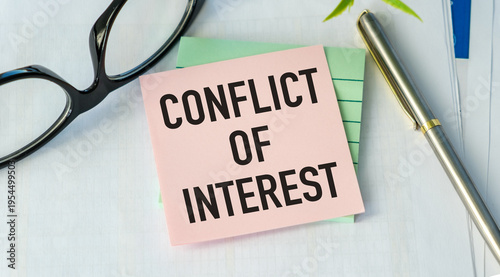 Conflict of Interest Concept: Pink Sticky Note with Bold Text on Office Desk with Pen and Glasses