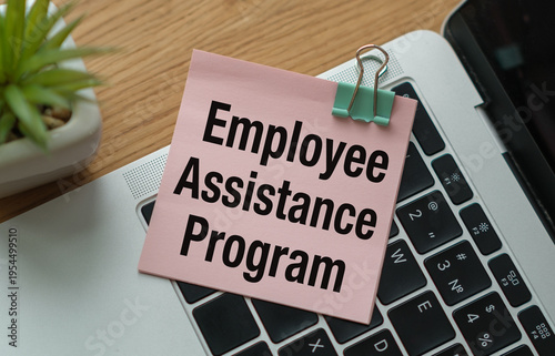A top-down close-up shot of a pink square sticky note with the words Employee Assistance Program in bold black font.