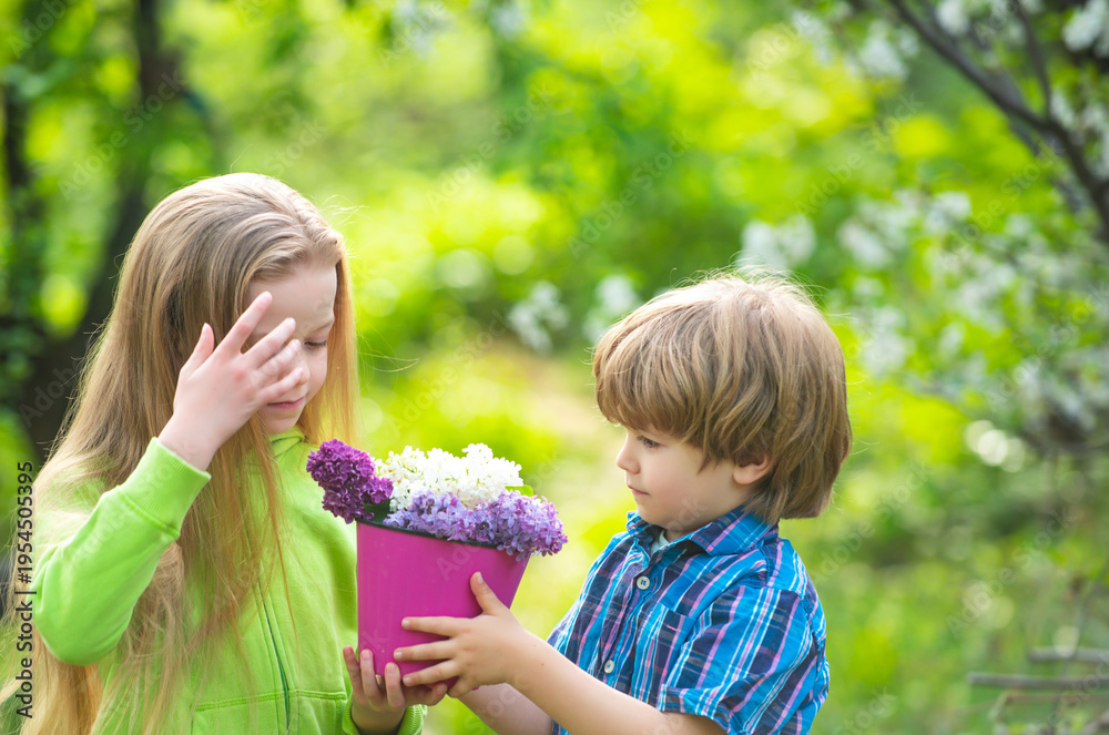 Obraz premium Spring kids smiling in garden with flowers. Spring garden teamwork with brother and sister. Spring gardening moment with fresh plant. Spring garden fun and nature.