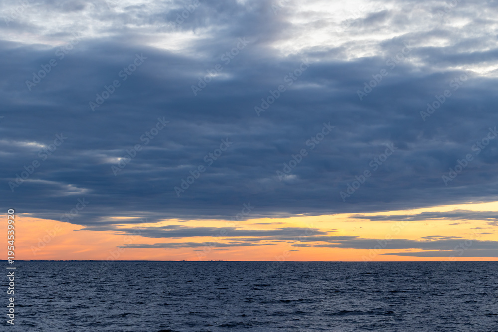 Obraz premium Coastal landscape photo featuring dark cloudy sky over the horizon at sunset. Baltic Sea landscape
