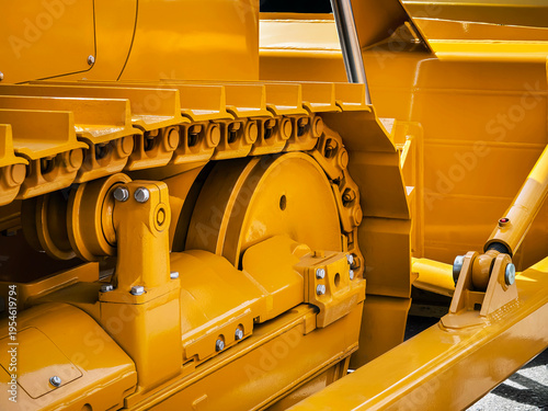Close view of a yellow bulldozer showing the track and mechanical parts on a construction site during midday
