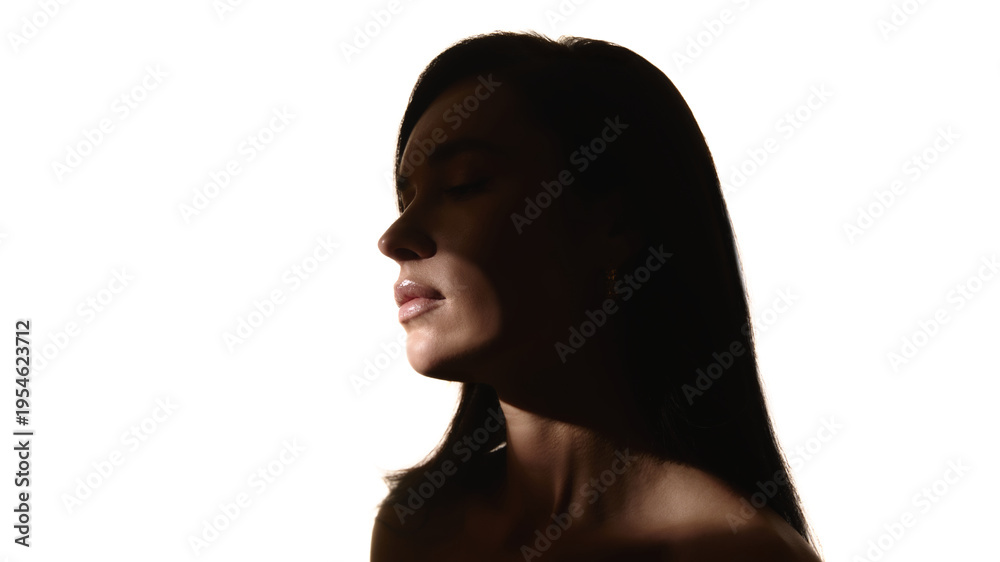 Fototapeta premium Female portrait in dramatic shadow light minimalist beauty studio. Concept of skincare advertising, cosmetic branding, beauty treatment and wellness marketing.