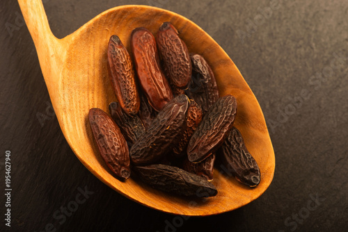 Tonka Beans on Wooden Spoon over Slate Background