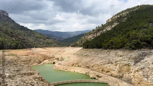 A reservoir with azure water in the mountains of Spain, a trail near Montanejos, Castellon. A dam covers the river for safety during heavy rains. A popular place for active recreation. The Arenos