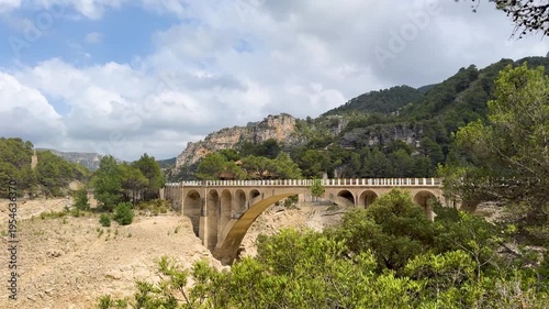 A reservoir with azure water in the mountains of Spain, a trail near Montanejos, Castellon. A dam covers the river for safety during heavy rains. A popular place for active recreation. The Arenos