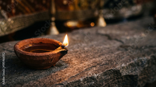 Tableau sur toile Clay oil lamp burning on rough stone surface during evening outdoor ritual creat
