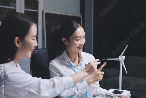 
 Two business people team planning and discussing of sustainable and renewable clean energy product with solar cell and wind turbine generator, CO2 emissions climate change global warming project