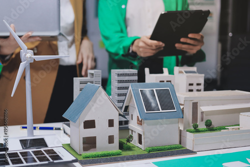 
 Two business people team planning and discussing of sustainable and renewable clean energy product with solar cell and wind turbine generator, CO2 emissions climate change global warming project