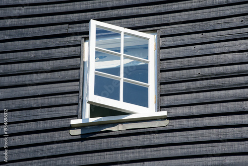 Tableau sur toile open wooden window in black clapboard wall