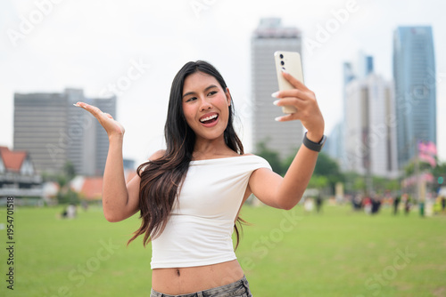 Cute woman smiling outdoors at Merdeka Square with Kuala Lumpur city skyline and a green park field