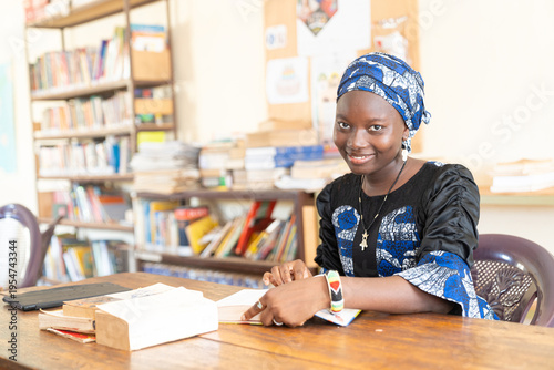 Young African female reader at the library consulting a dictionary