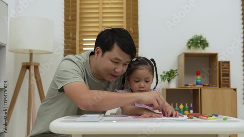 father and child girl drawing and painting with colorful oil pastels on paper at home