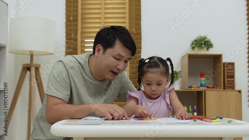 father and child girl drawing and painting with colorful oil pastels on paper at home