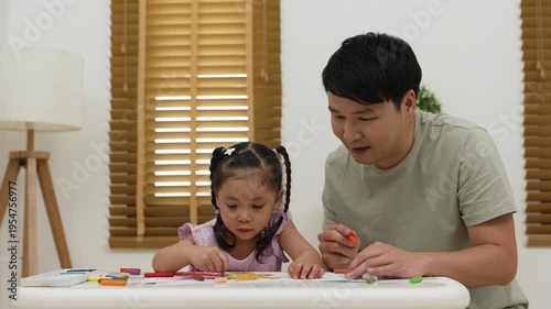father and child girl drawing and painting with colorful oil pastels on paper at home
