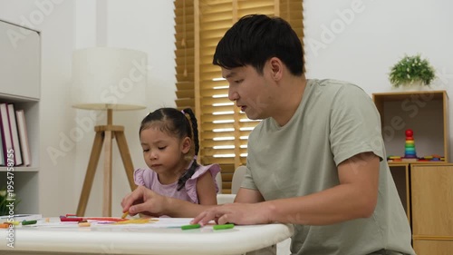 father and child girl drawing and painting with colorful oil pastels on paper at home