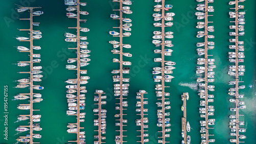Aerial view of numerous white boats docked neatly in rows on the turquoise water of Port du Bloscon, creating a striking contrast, Roscoff, France.