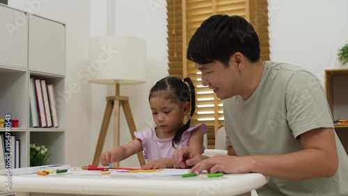 father and child girl drawing and painting with colorful oil pastels on paper at home