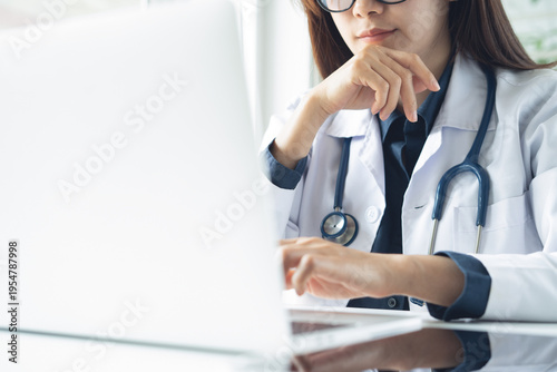 Female doctor working at laptop in hospital office, using medical online service, application for telemedicine service with patient or online meeting, web conference