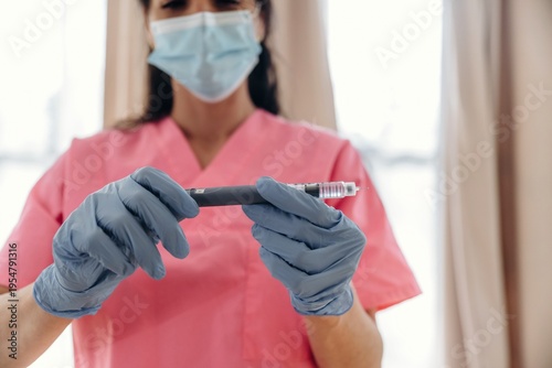 Wallpaper Mural Healthcare professional in pink scrubs wearing gloves and a mask holds an insulin pen for diabetes management in a well-lit medical environment Torontodigital.ca