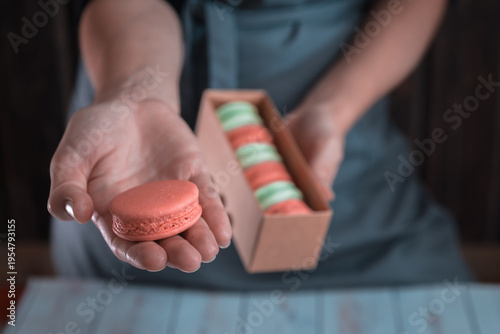 Female hand offering macaron with box of macarons bakery dessert concept