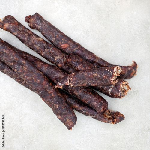 Tableau sur toile Droewors dried sausage snack on grey background with copy space