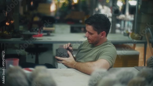 Skilled Male Creator Analyzes Spherical Artwork Amid Tools And Molds On Cluttered Work Station