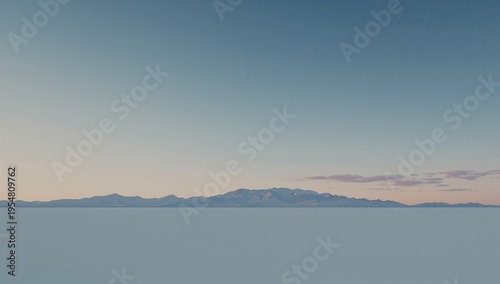 Framing distant mountain range stretching across pale salt flat plain at horizon, with wispy clouds
