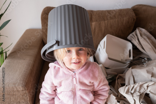 Funny 4 year old girl playing and putting a new trash can on her head