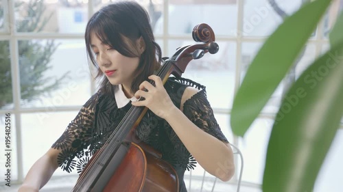 Beautiful young woman musician cellist rehearsal and performance of cello in concert hall classical music orchestral instrument string, focused bow moves smoothly across the strings on stage