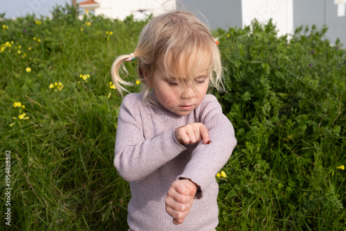 Curious little 4 year old girl examining a ladybug on her hand
