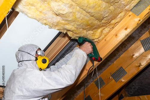 Man installing mineral wool insulation in attic roof
