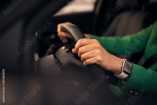 Woman driving a car wearing smartwatch and green jacket