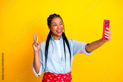 Schilderij op canvas Young woman taking a selfie with peace sign against bright yellow background