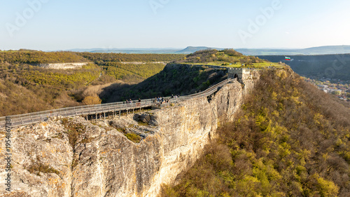 Aerial exploration of Ovech Fortress in Bulgaria during spring time. Detailed view of the wooden bridge walkway on high vertical cliffs near Provadia. History and scenic nature combination.