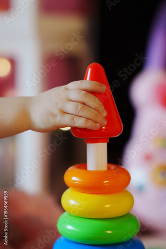 Child playing with colorful stacking rings in indoor space