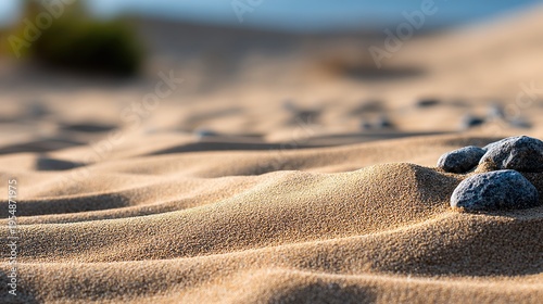Sunlight reflects on sand forming ripples and shapes on a beach. The scene shows a light atmosphere with warm colors