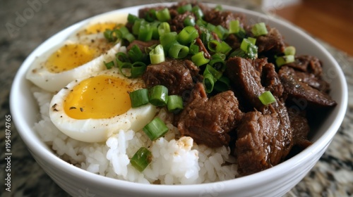 Delicious bowl of tender beef served with soft-cooked eggs and fresh green onions over fluffy white rice, perfect for meals or culinary presentations