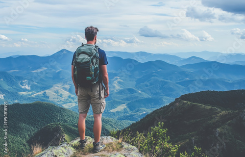 Adventurous hiker standing on mountain peak overlooking vast landscape representing exploration freedom and outdoor travel lifestyle concept