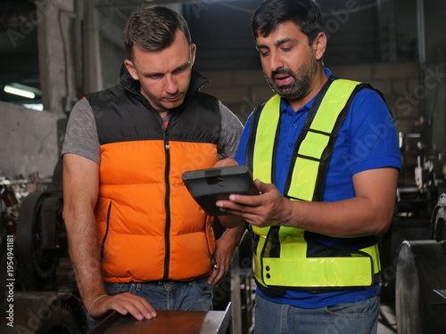 Industrial engineers inspecting machinery using tablet in factory workshop