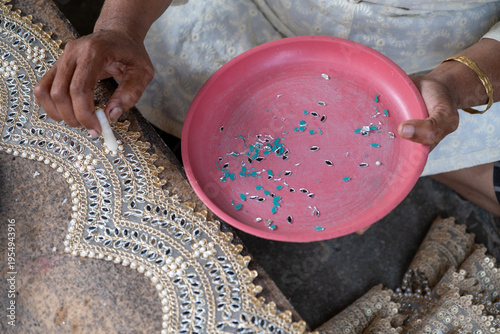 Indian woman making traditional beadwork jewelry, close-up of hands with colorful beads and handcrafted textile