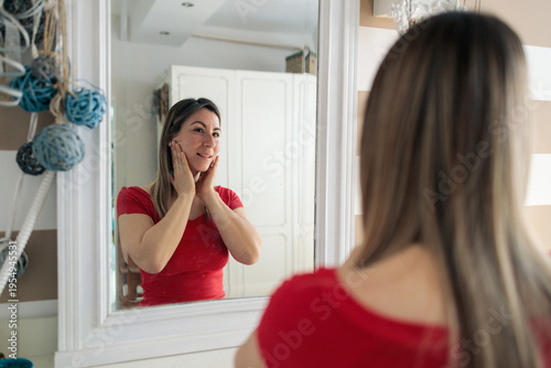 Woman checking her skin in bathroom mirror