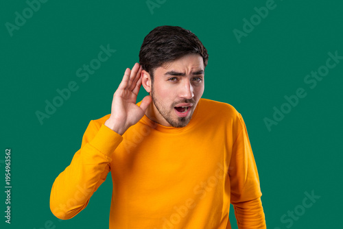 Young Man Pointing To Ear With Confused Face, Signaling He Cant Hear Clearly