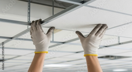 Installation of ceiling tiles with hands wearing gloves in a modern interior setting, demonstrating repair work and maintenance techniques for home improvement projects. Concept for repair services.